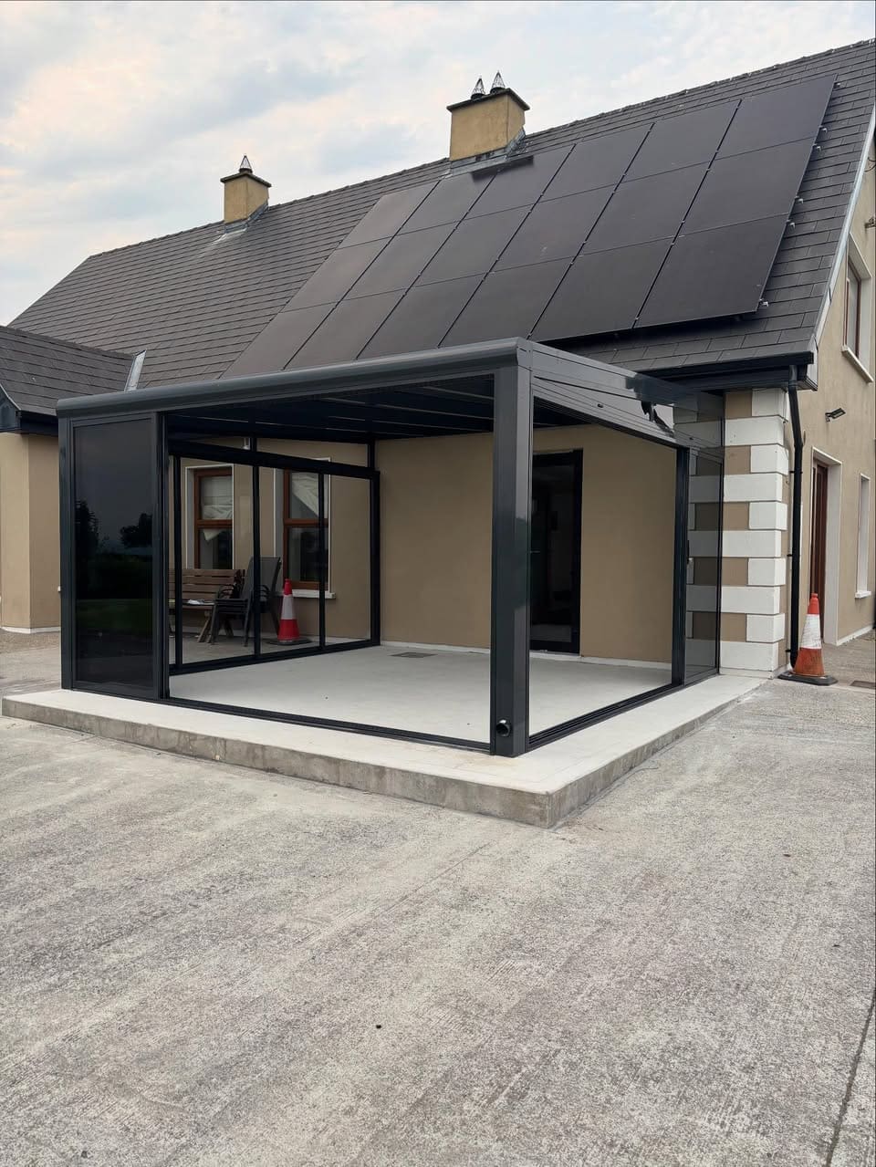 Fully enclosed aluminium pergola with sliding glass doors open creating indoor outdoor garden space