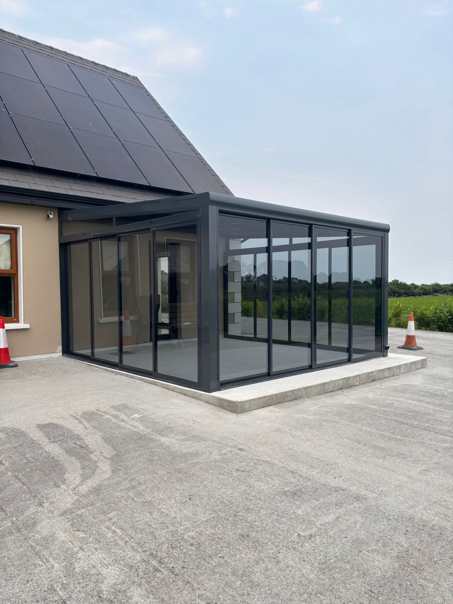 Fully enclosed tinted glass pergola with sliding doors used as a garden room in Ireland